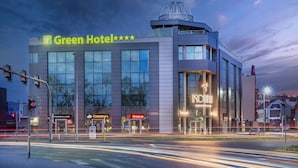 Ein modernes Hotel mit einem gut sichtbaren Schild 'Green Hotel', einem Restaurant namens 'KOKO' und einer Bar namens 'Orange'.