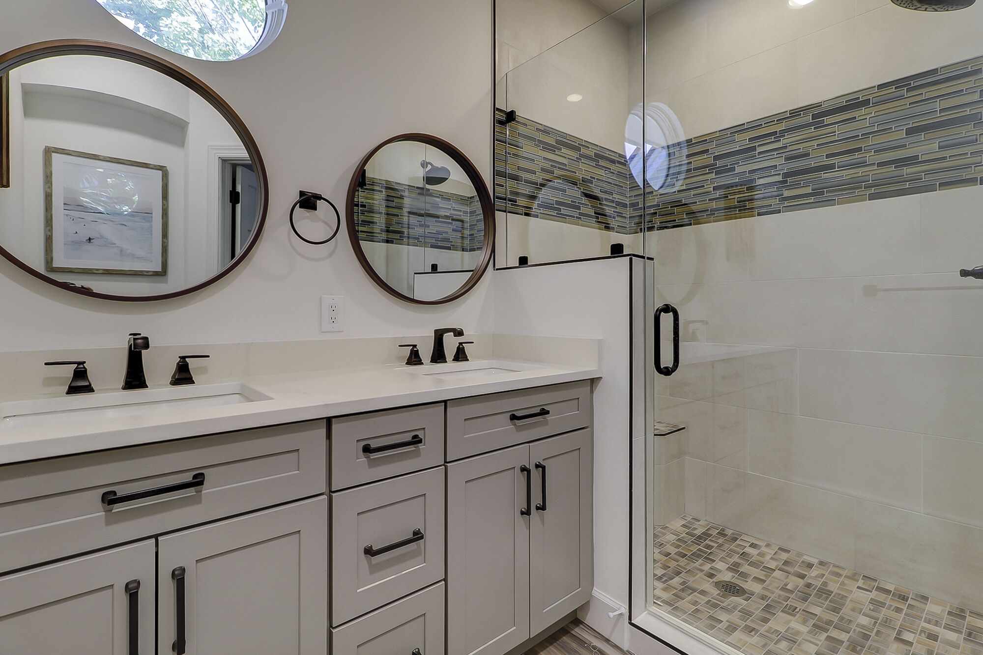 A modern bathroom with a glass shower enclosure, a white vanity with a large mirror, and a tiled backsplash.