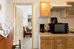A compact kitchen with wooden cabinets, a microwave, and a coffee maker.