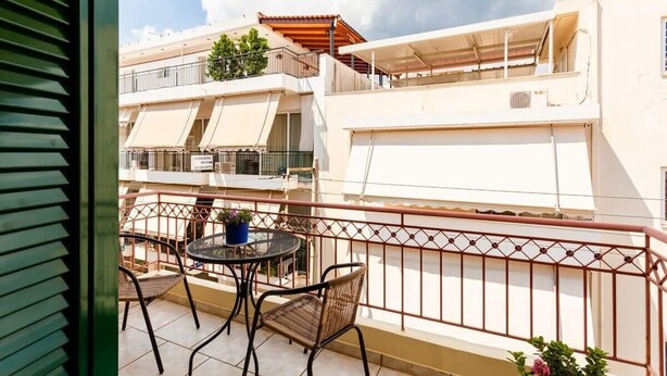 Un balcón con mesa y sillas, con vistas a una zona residencial con varios edificios.