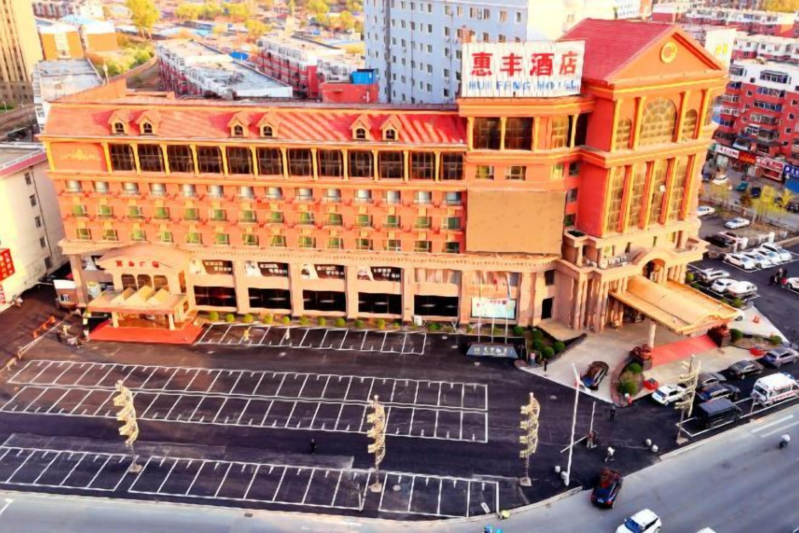 Un hotel de varios pisos con techo rojo y un estacionamiento al frente.