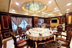 Un comedor lujoso con una mesa redonda, sillas ornamentadas y una lámpara de araña.