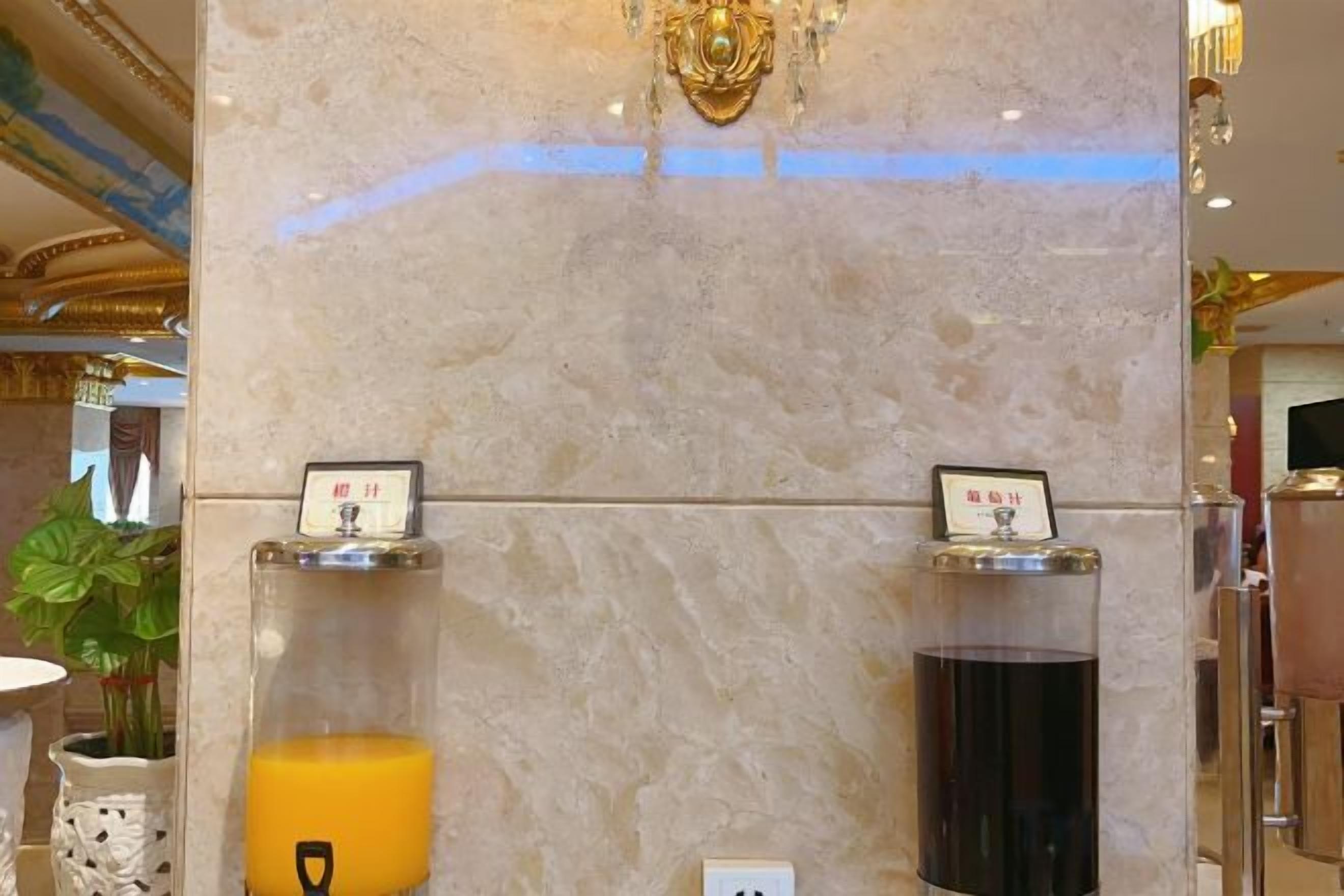 A marble wall with two beverage dispensers, one dispensing orange juice and the other a dark beverage, likely coffee or tea.