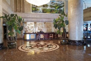 Un vestíbulo con mostrador de recepción, amplias columnas y un diseño decorativo en el suelo.