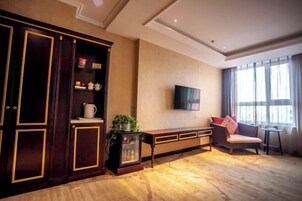 Una sala de estar con un mueble bajo de madera oscura, un televisor de pantalla plana, un sofá y un ventanal con cortinas.