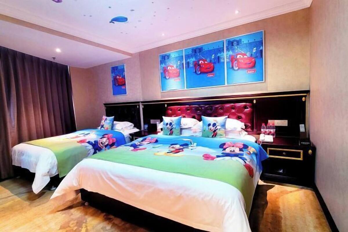 A hotel room with two beds, a large window, and a ceiling with a starry design.