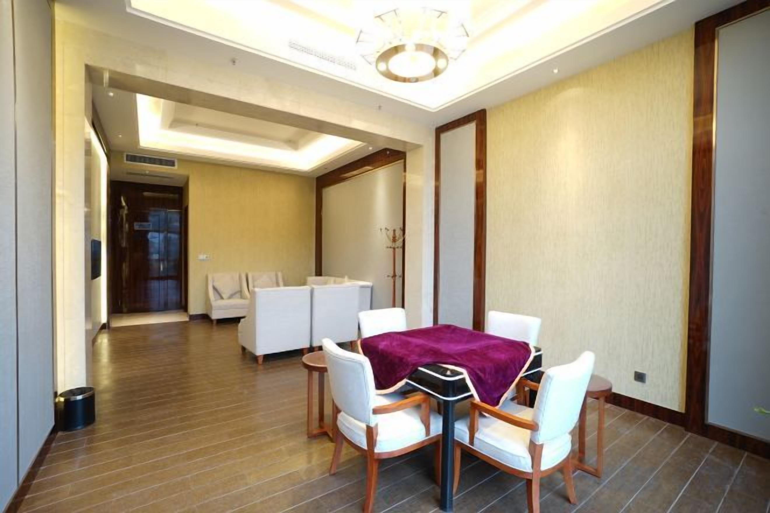 A modern hotel room with a dining area, a sofa set, and a wooden floor.