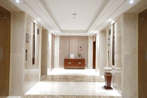 Een hotelhal met een marmeren vloer, een receptiebalie en een klok aan de muur.