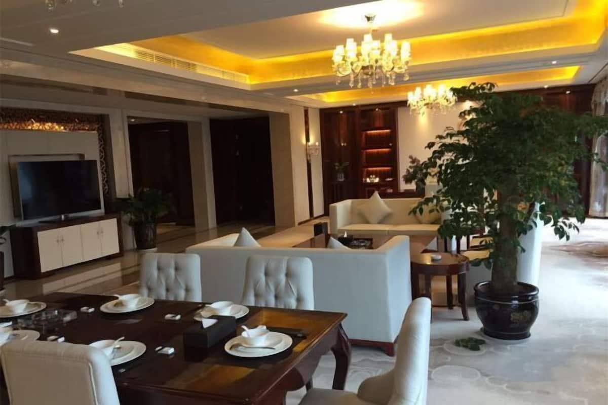 Een moderne hotel lobby met een eetgedeelte, banken, een kroonluchter en een grote potplant.