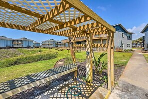A wooden pergola structure with a garden area in front of a residential building. - 'Sea-King Sol' Ocean-View Condo in Port Aransas! (Port Aransas)