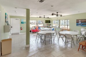 A spacious room with a large round table, multiple chairs, ceiling fans, and a television. - 'Sea-King Sol' Ocean-View Condo in Port Aransas! (Port Aransas)