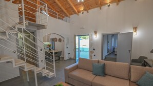 A spacious living area with a high ceiling, a staircase, a sofa, and a dining area. - Villa Garifalia with Sauna & Hydromassage (Apokoronas)