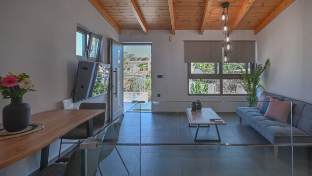 A modern living room with a wooden ceiling, a sofa, a coffee table, and a TV. - Villa Garifalia with Sauna & Hydromassage (Apokoronas)