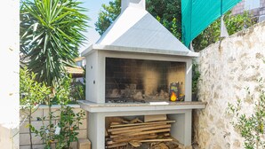 An outdoor brick grill with a chimney, surrounded by potted plants and a stone wall. - S2 - Modern Studio, Just 50m From the Beach (Korcula)