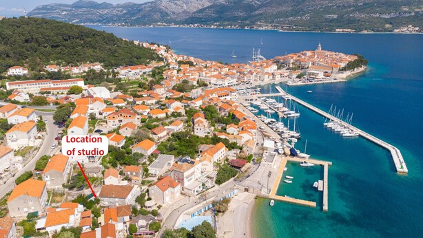 An aerial view of a coastal town with a marina, buildings with orange roofs, and a marked location of a studio. - S2 - Modern Studio, Just 50m From the Beach (Korcula)