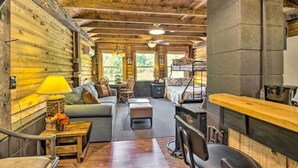 Interior acolhedor de uma cabana com teto de madeira, área de jantar e um sofá.