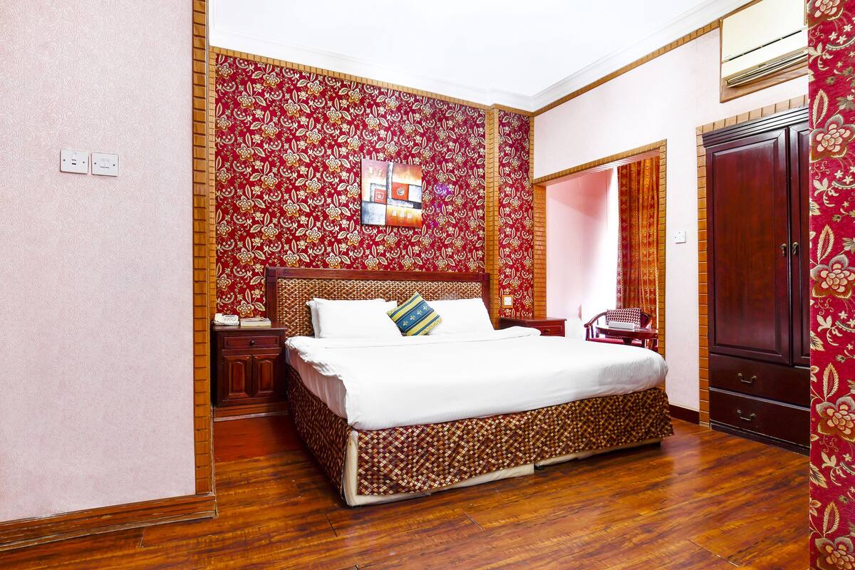 Une chambre à coucher avec un grand lit, une armoire et un miroir.