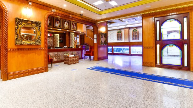 A lobby with a reception desk, a chandelier, and a blue carpet. - OYO 125 Moon Plaza Hotel (Manama)