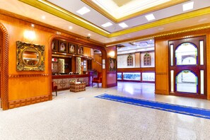 A lobby with a reception desk, a chandelier, and a blue carpet. - OYO 125 Moon Plaza Hotel (Manama)