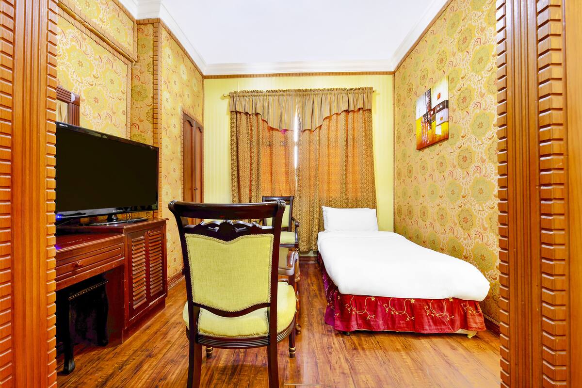Une chambre d’hôtel équipée d’une télévision, d’un lit, d’une chaise et d’un bureau.