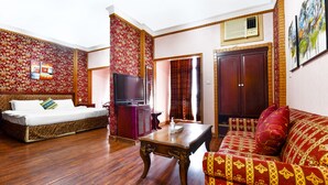 A room with a wooden floor, a sofa, a TV, a cabinet, and a door. - OYO 125 Moon Plaza Hotel (Manama)
