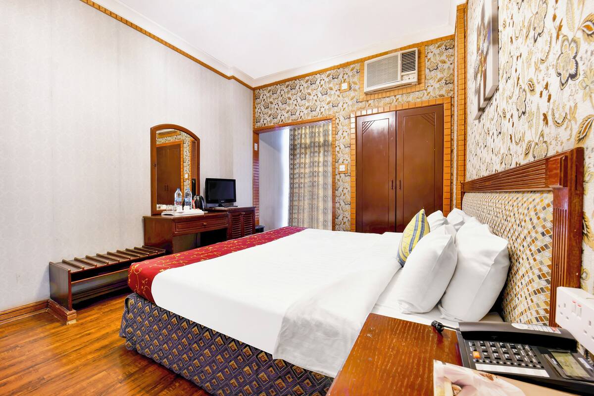 Une chambre d’hôtel comprenant un lit, un bureau avec un téléphone, une télévision et une armoire.