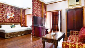 A room with a sofa, a TV, a wooden table, and a patterned wall.