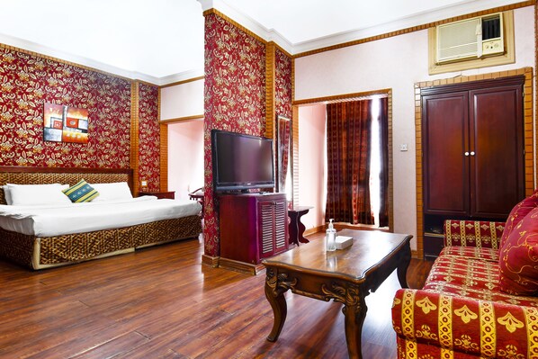 A room with a sofa, a TV, a wooden table, and a patterned wall. - OYO 125 Moon Plaza Hotel (Manama)