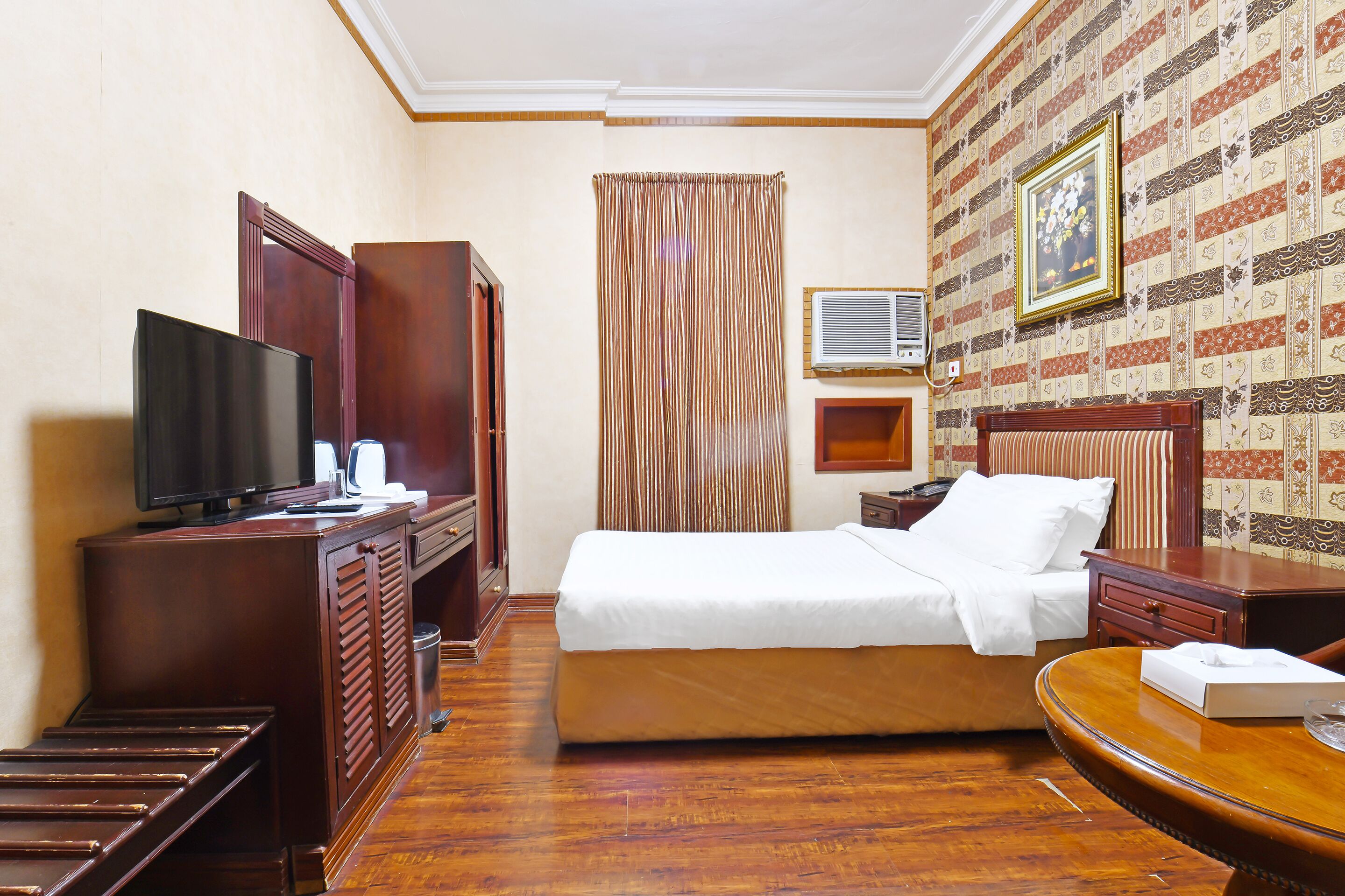 A hotel room with a bed, a television, a desk, and a wardrobe.