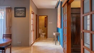 A hallway with a dining area, a toilet, and a large wooden door.