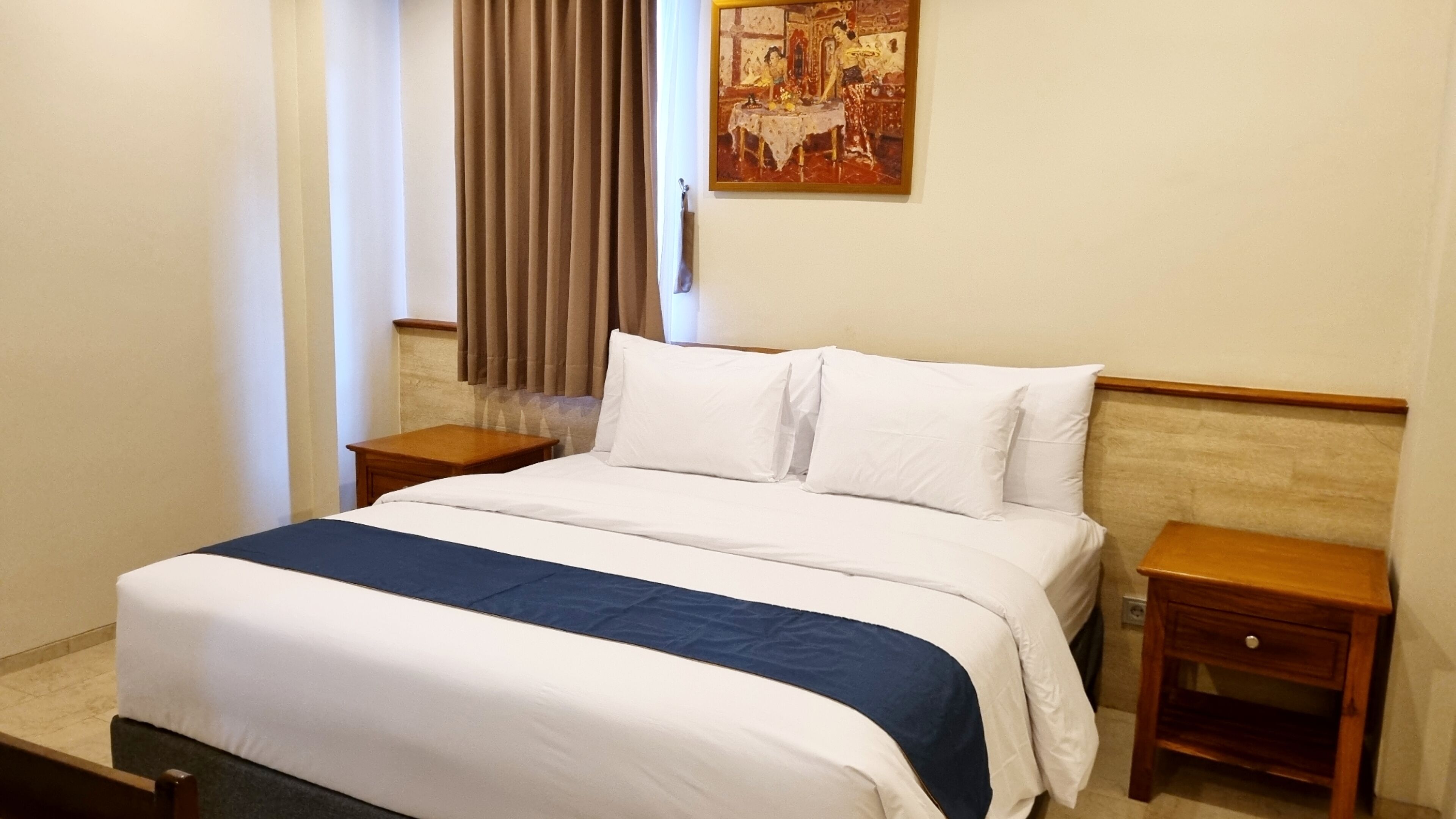 A hotel room with a bed, two bedside tables, a painting on the wall, and a window with curtains.