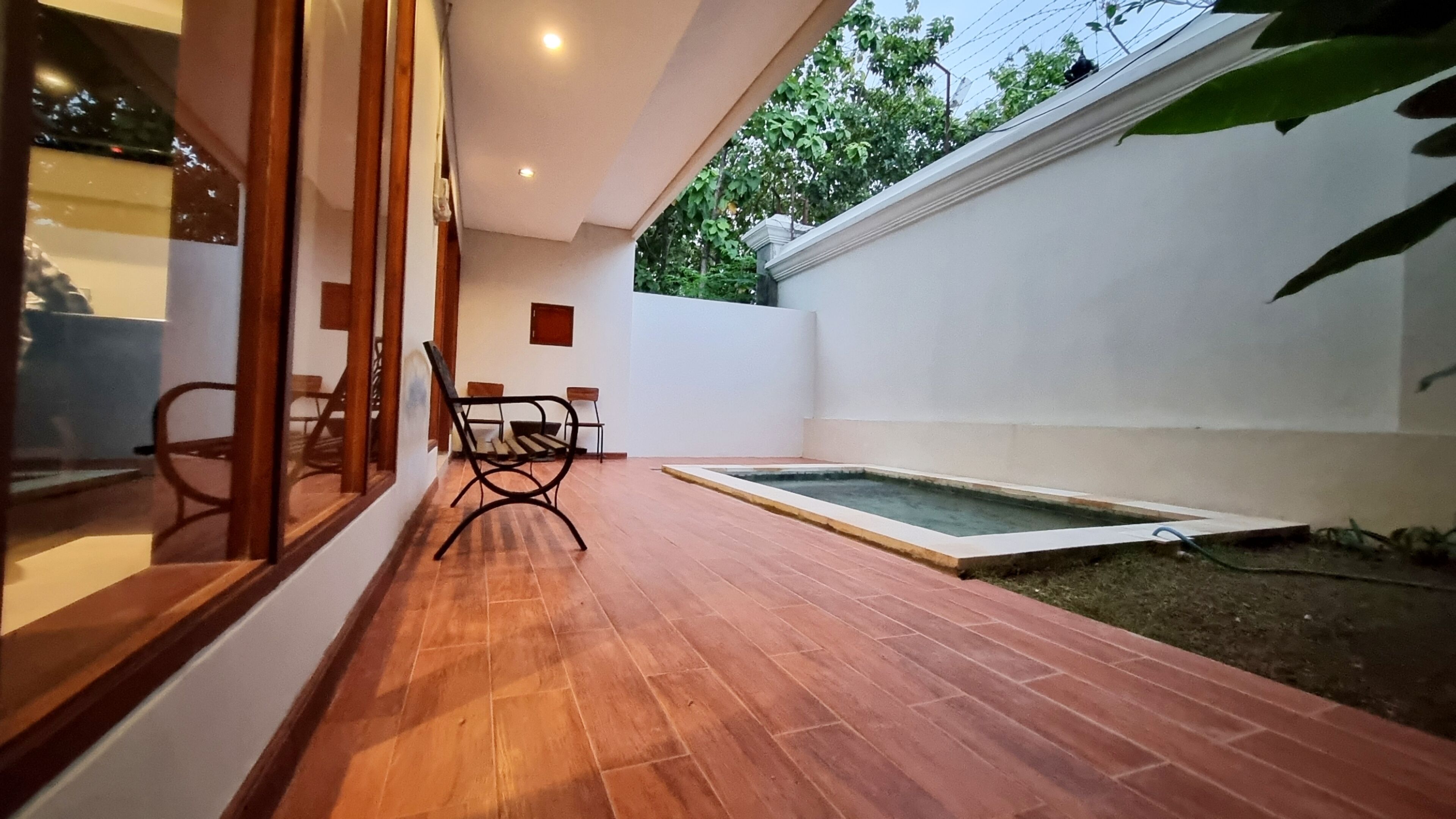 A patio with wooden flooring, a small pool, and a seating area with chairs.