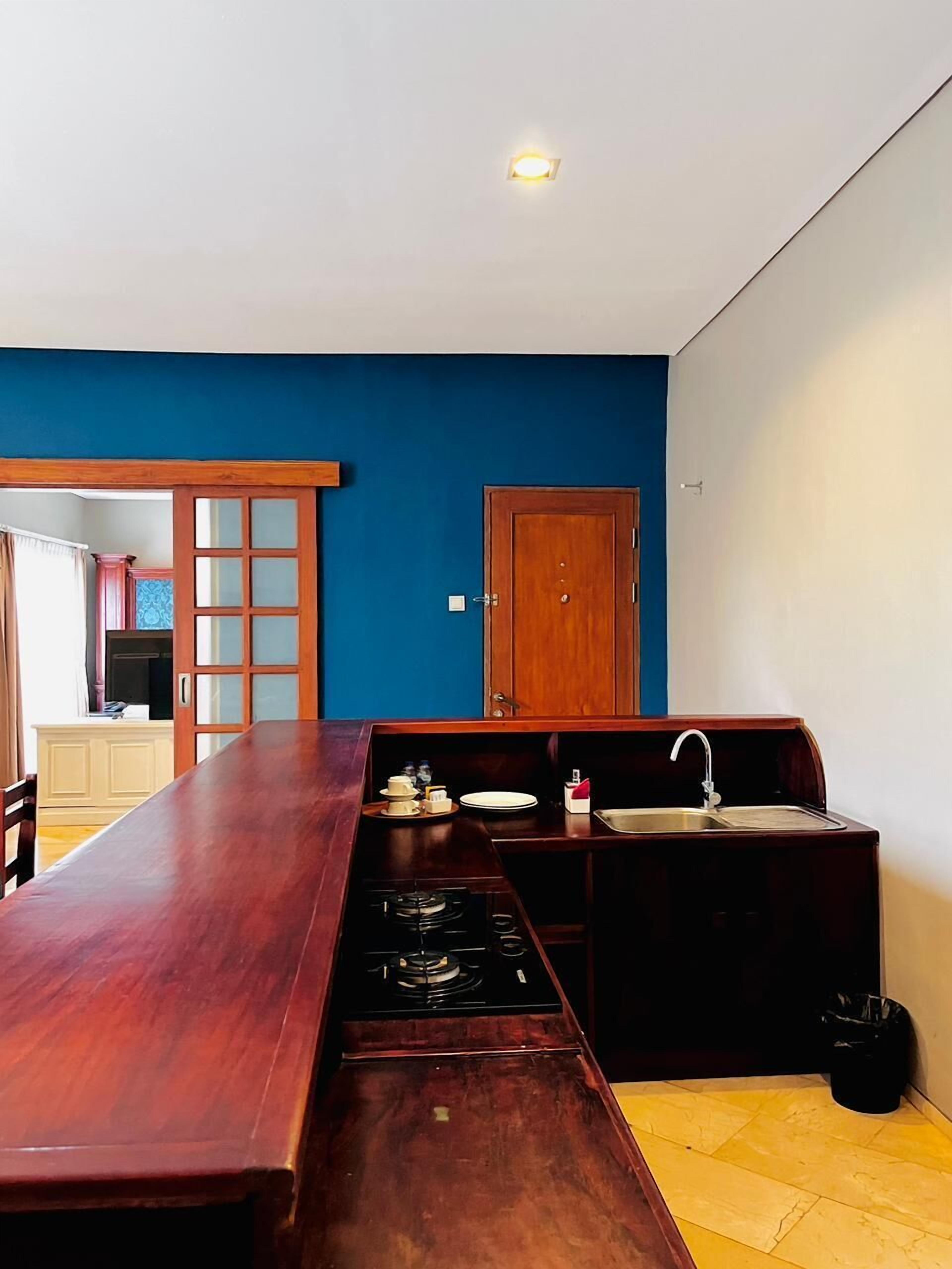 Een keuken met een houten tafel, een fornuis, een spoelbak en een deur.
