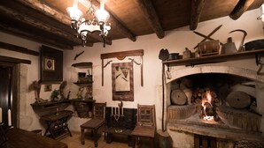 Ein rustikales Interieur mit Kamin aus Stein, Holzmöbeln und diversen Küchenutensilien.