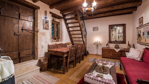 Ein rustikaler Raum mit einem Holzesstisch, einer Couch, einer Leiter und einem Chandelier.