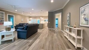 Un'ampia zona giorno con un divano blu scuro, un tavolino da caffè bianco e un consolle bianco con oggetti decorativi.