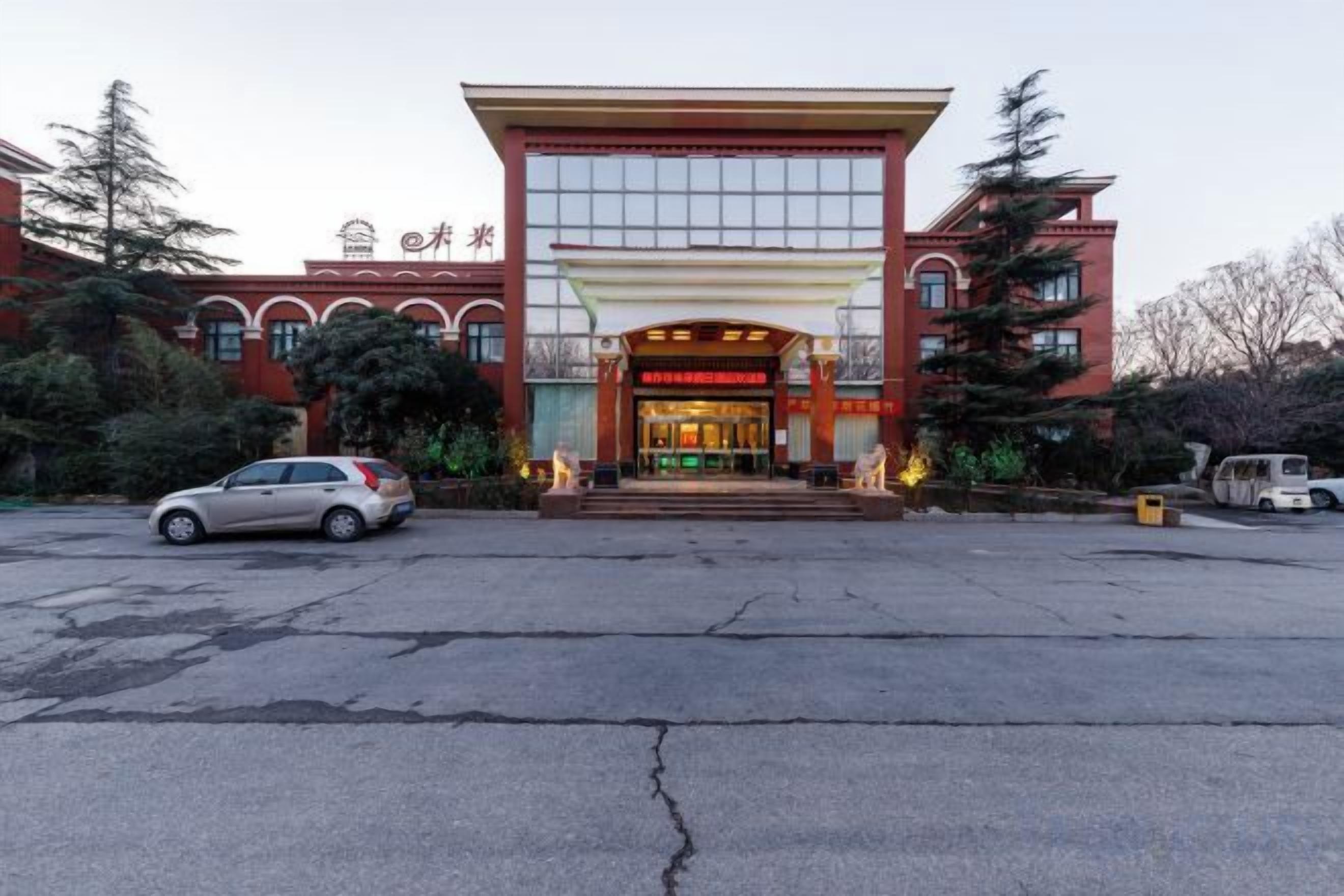 A hotel with a red facade, a large entrance, and a parking lot.