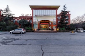 Un hôtel à la façade rouge, doté d’une grande entrée et d’un parking.