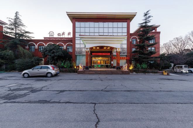 A hotel entrance with a red facade, large windows, and a covered entrance area.