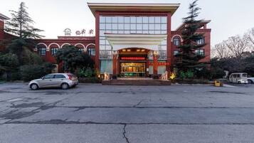 A hotel entrance with a red facade, large windows, and a covered entrance area.