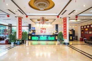 A hotel reception area with a polished floor, a reception desk, and red pillars.