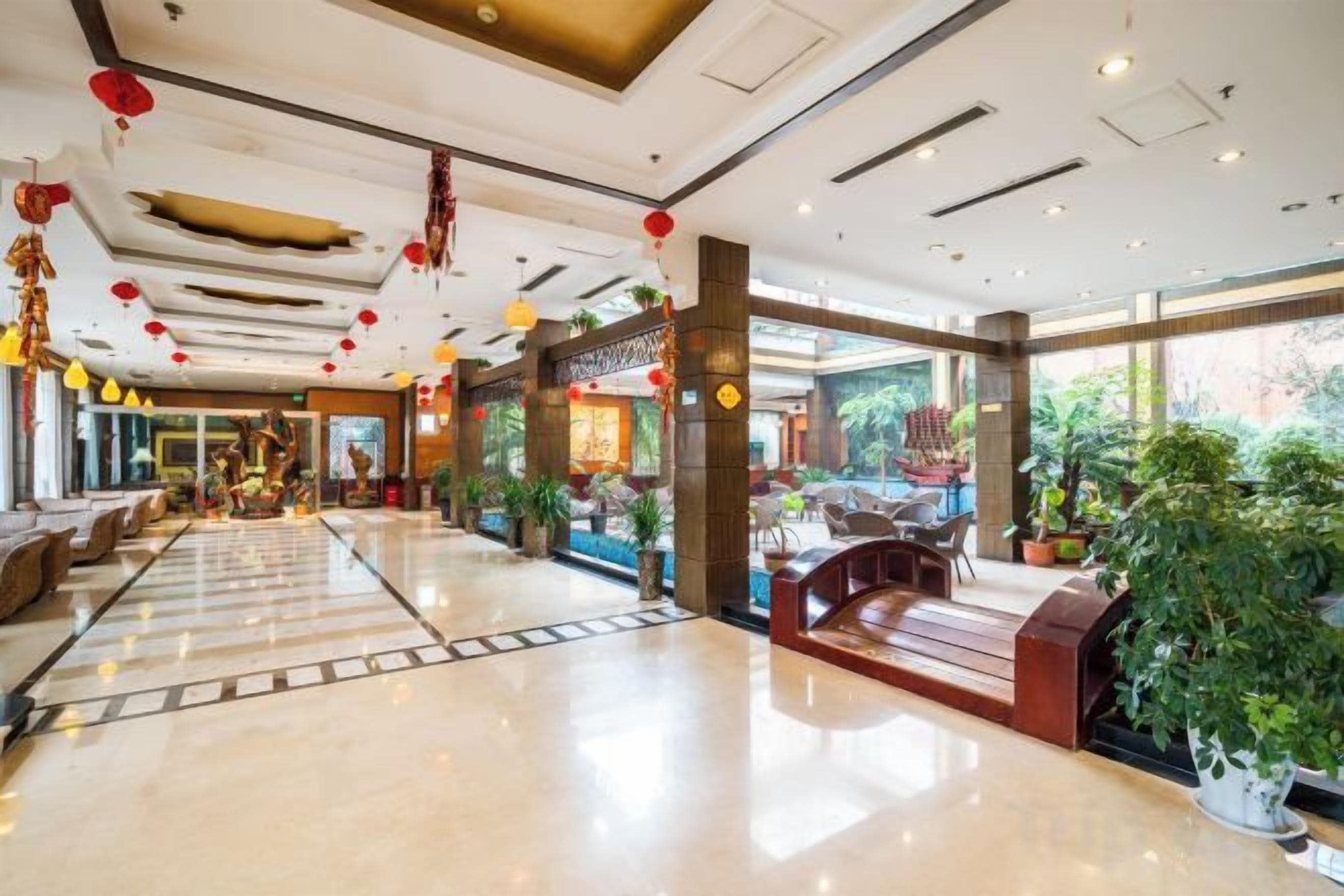A hotel lobby with a polished floor, seating areas, and large windows.