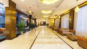 A hotel lobby with a marble floor, seating areas, and a reception desk.