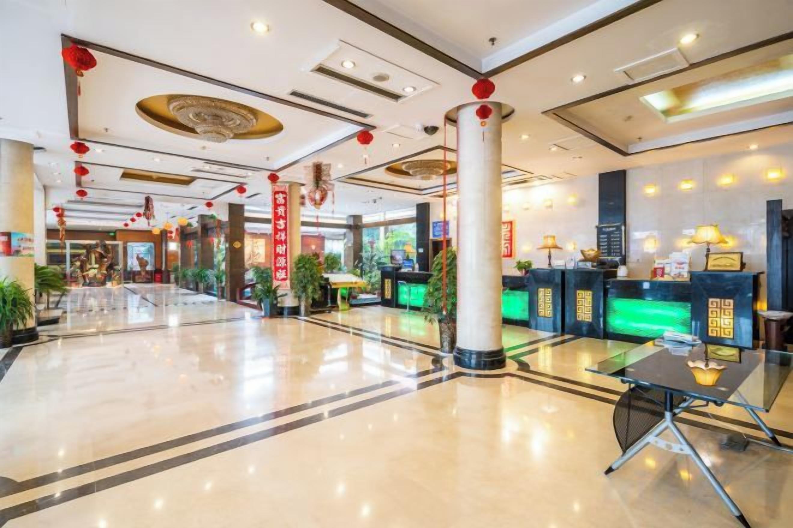A hotel lobby with a reception desk, seating area, and decorative elements like columns and plants.