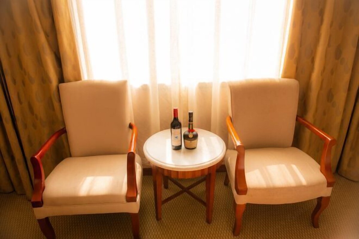 Two armchairs facing each other with a small round table between them, holding two bottles of wine.