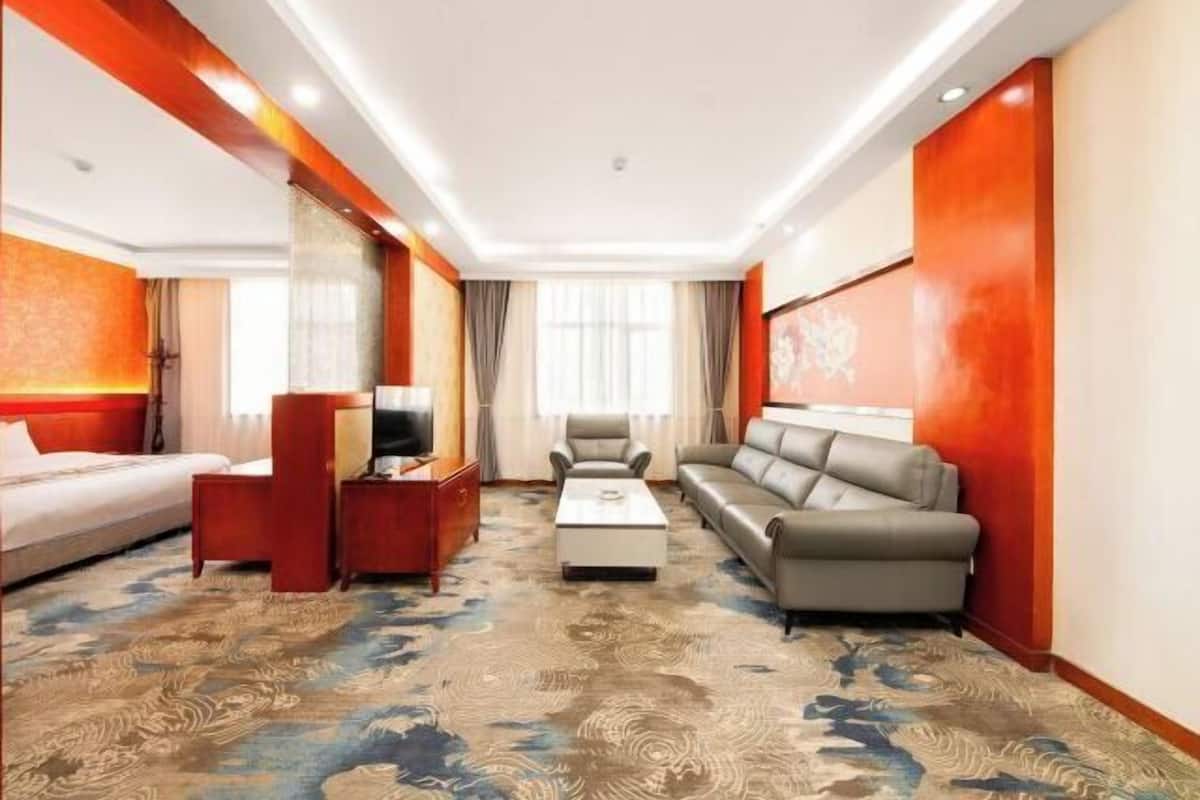Une chambre d’hôtel comprenant un lit, un canapé, une table basse, un téléviseur et un sol recouvert de moquette.