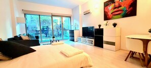 Een moderne hotelkamer met een groot bed, een televisie, een zithoek en een balkon met uitzicht.