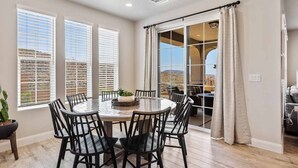 A dining area with a round table and chairs, large windows with blinds, and a view of the outdoors. - A Family Affair, Sleeps 20 in two side-by-side units, 10 bedrooms! (Washington)