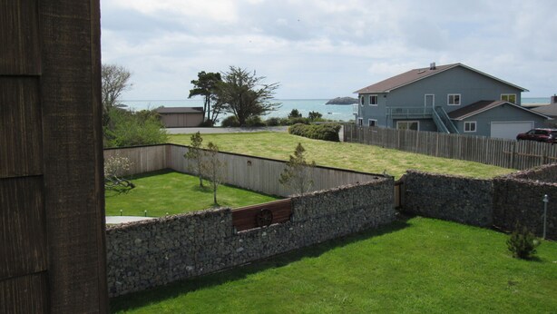 A residential backyard with a stone wall, a wooden fence, and a grassy lawn.