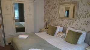 A bedroom with a large bed, a wardrobe, a nightstand, and a mirror on the wall. - 5 Bedrooms, Sleeps 10-12 w/ Wifi, Parking & Garden (Leven)